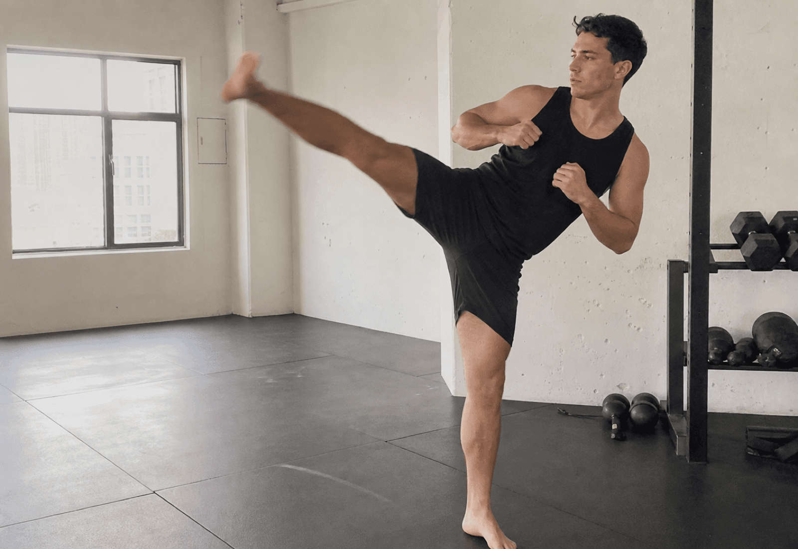 Atleta entrenando una patada alta controlada en un estudio limpio